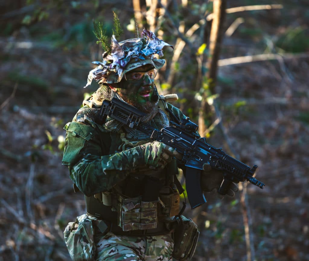 joueur d'airsoft en forêt avec sa réplique de glock 19 