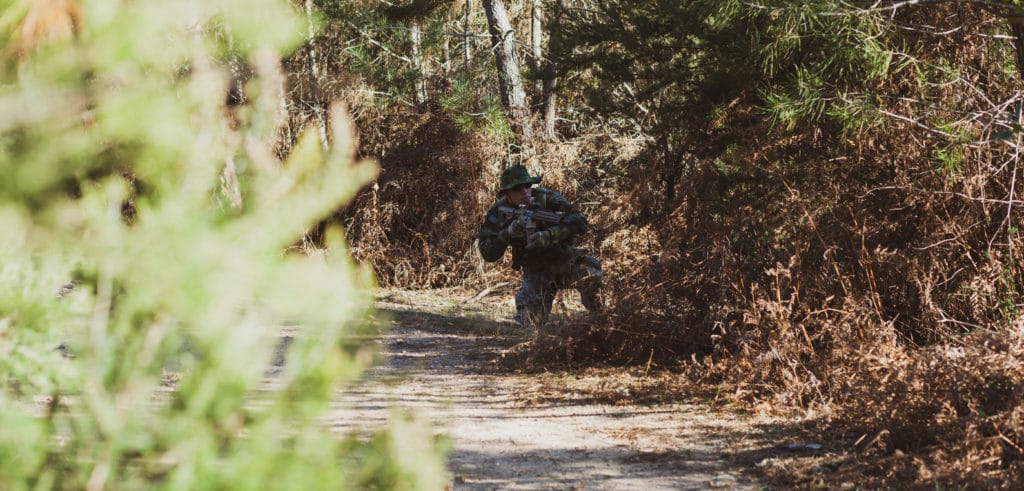 Joueur d'airsoft en forêt avec sa réplique ump 45 